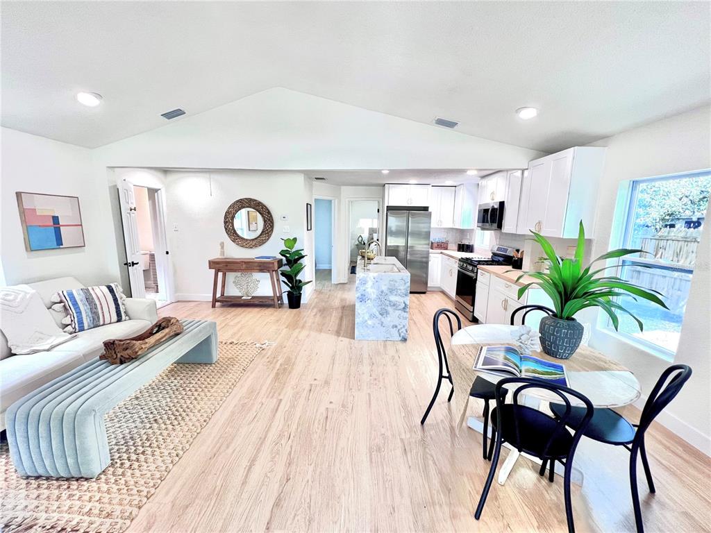 An open-concept living room and kitchen with light wood floors and a marble-topped island — 2427 32ND AVENUE N, ST PETERSBURG, FL