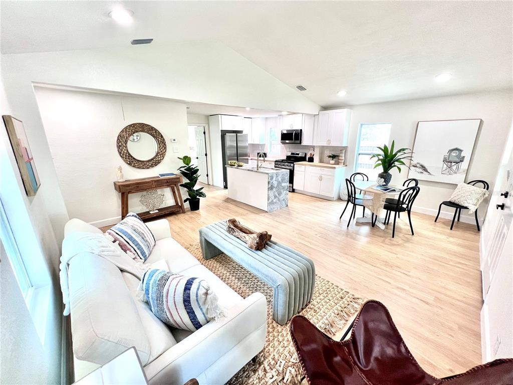 An open-concept living room and kitchen featuring light wood flooring and white cabinetry — 2427 32ND AVENUE N, ST PETERSBURG, FL