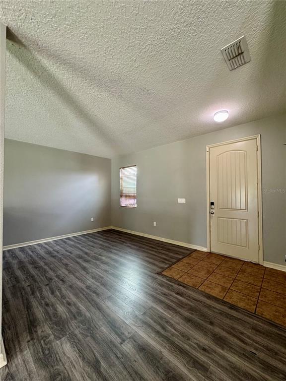 An entryway with a tiled floor transitions into a living area with wood-look flooring — 998 HERMOSA WAY, KISSIMMEE, FL