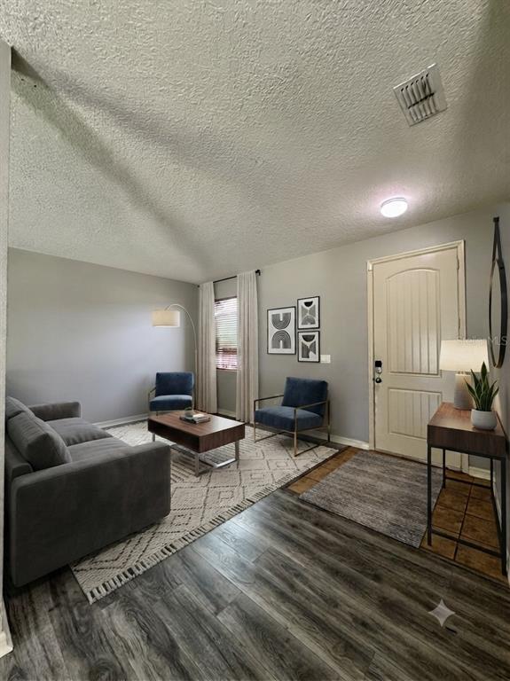 A living room features gray walls, wood-look flooring, a sofa, two armchairs, and an entryway door — 998 HERMOSA WAY, KISSIMMEE, FL