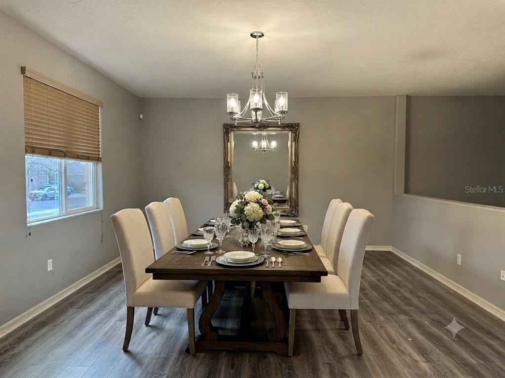 A dining room features a wooden table with six chairs, a chandelier, and a large mirror — 998 HERMOSA WAY, KISSIMMEE, FL