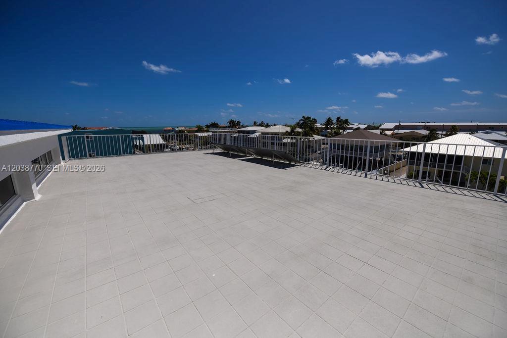 A rooftop deck features light-colored square tiles, a white metal railing, and solar panels — 177 Lorelane Pl, Key Largo FL 33037, KEY LARGO, FL