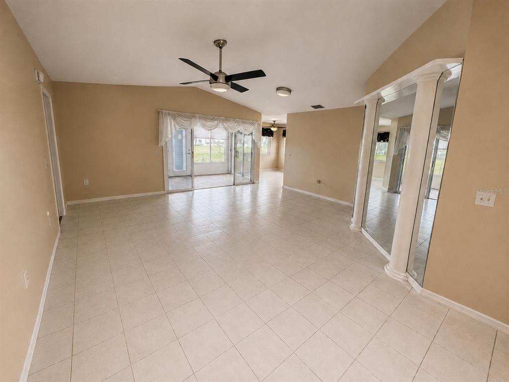 A spacious living area features light tile flooring, a ceiling fan, and mirrored wall panels — 3526 INNISBROOK DRIVE, LAKELAND, FL