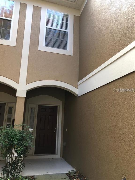 The exterior of a two-story townhouse features a brown stucco facade with white trim — 2850 POLVADERO LANE UNIT 105, ORLANDO, FL