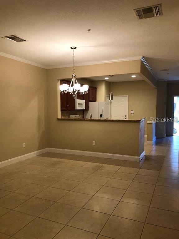 A dining area with tile floors leads to an open kitchen with a breakfast bar — 2850 POLVADERO LANE UNIT 105, ORLANDO, FL