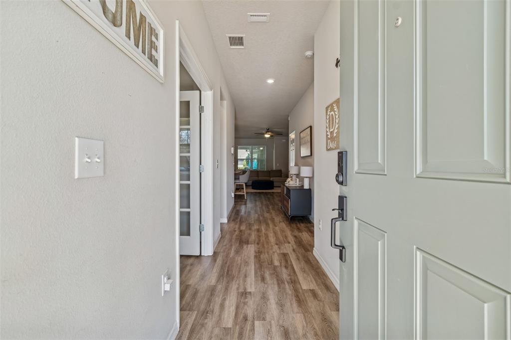 A view from an open front door looking down a hallway toward a living area — 14663 PROMENADE PARKWAY, ODESSA, FL