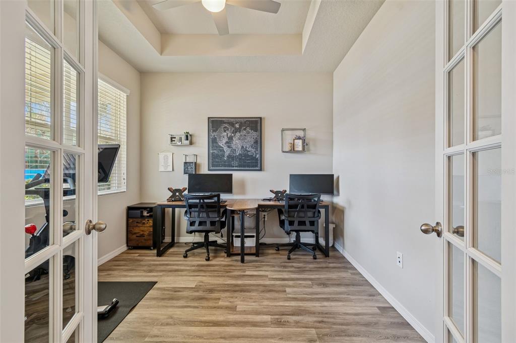 A home office with two desks, wood-look flooring, and French doors leading into the room — 14663 PROMENADE PARKWAY, ODESSA, FL