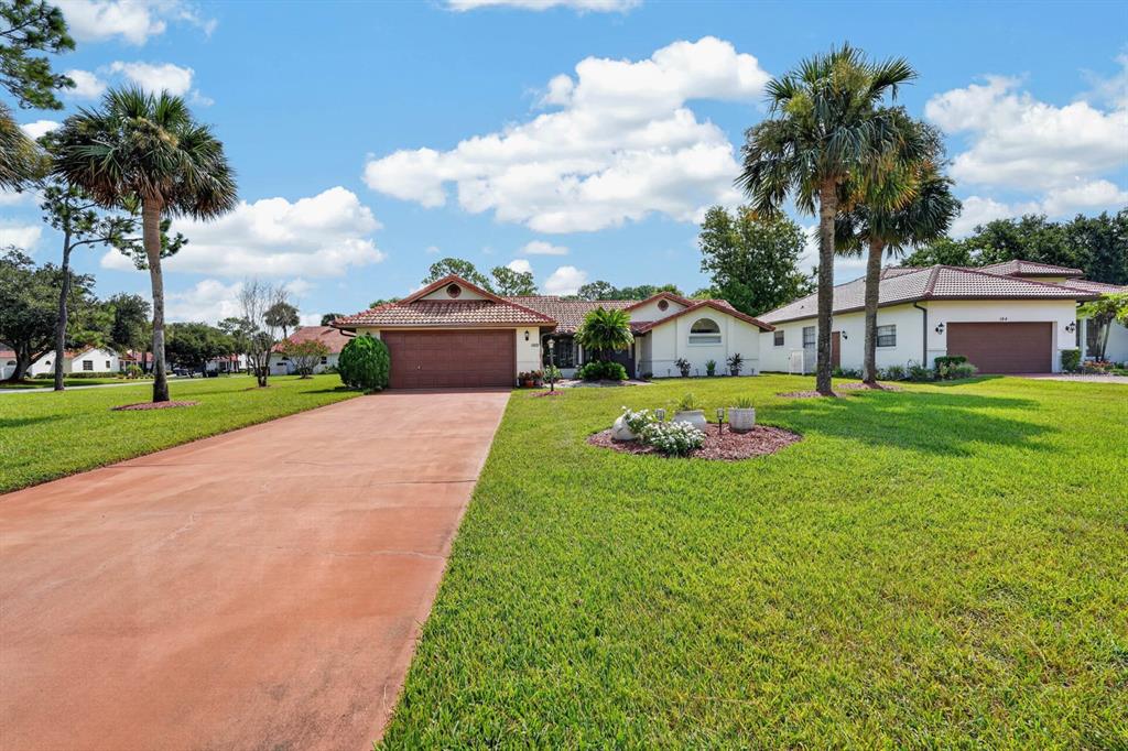 A single-story house with two garages, a long driveway, and palm trees on a lawn — 100 WATER TURKEY COURT, DAYTONA BEACH, FL