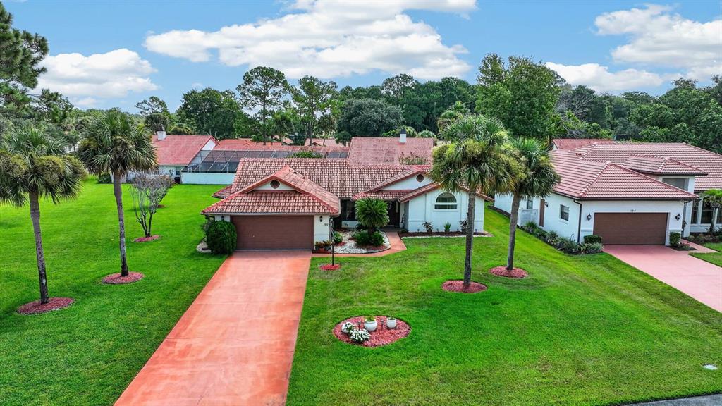 An aerial view shows a single-story house with a red tile roof and two garages — 100 WATER TURKEY COURT, DAYTONA BEACH, FL