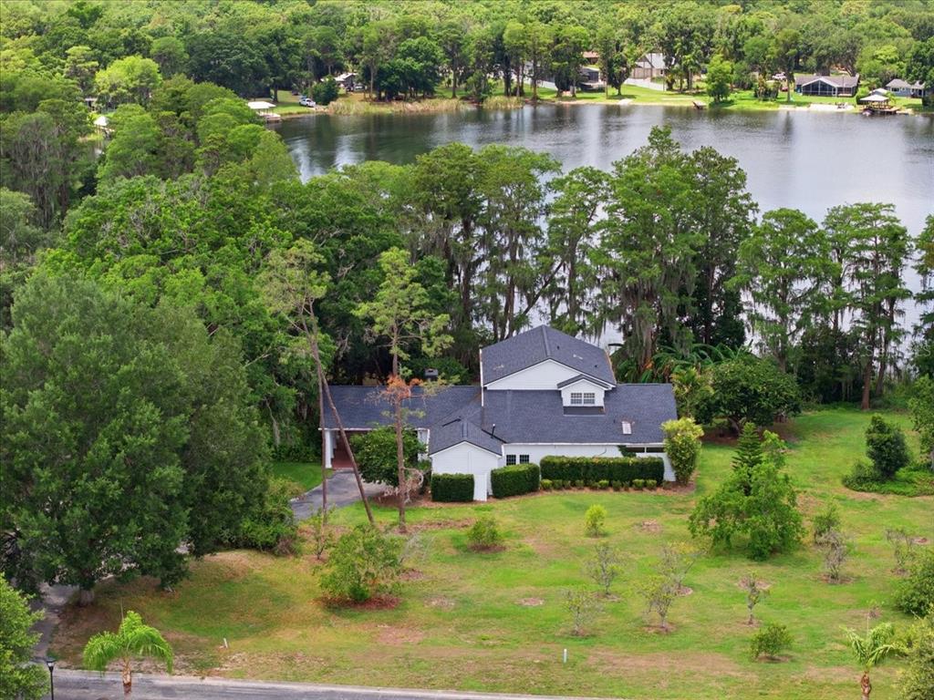 An aerial view of a white house with a dark roof situated near a lake — 15612 HOWELL PARK LANE, TAMPA, FL