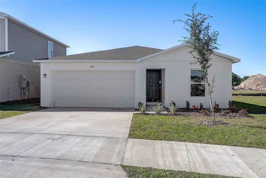 A single-story house with a white stucco exterior, a two-car garage, and a dark front door — 1296 GERRY ROAD SW, PALM BAY, FL