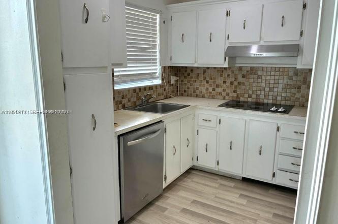 A kitchen features white cabinets, a stainless steel dishwasher, and a tiled backsplash — 609 S State Road 7 # 2D, Margate FL 33068, MARGATE, FL