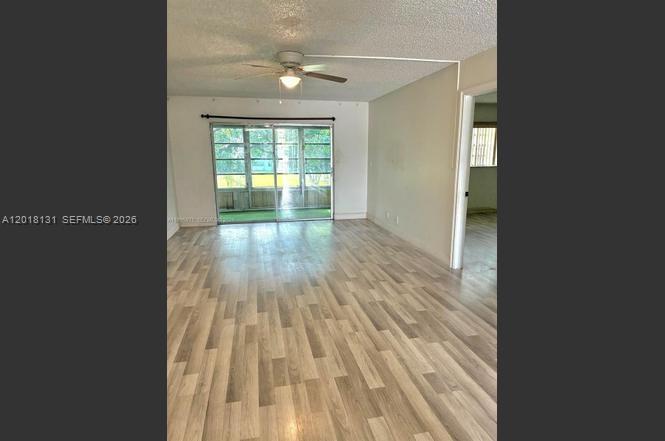 An empty living room features light wood-look flooring, a ceiling fan, and a sliding glass door — 609 S State Road 7 # 2D, Margate FL 33068, MARGATE, FL