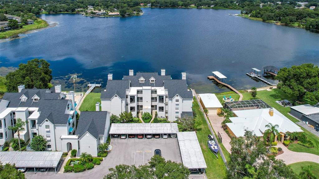 An aerial view shows a multi-story apartment building with covered parking next to a lake — 3127 W SLIGH AVENUE UNIT 204B, TAMPA, FL