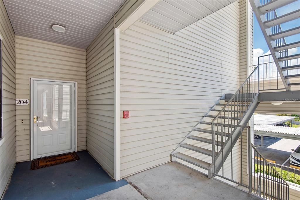 An exterior view of an apartment entrance with a white door and metal stairs — 3127 W SLIGH AVENUE UNIT 204B, TAMPA, FL