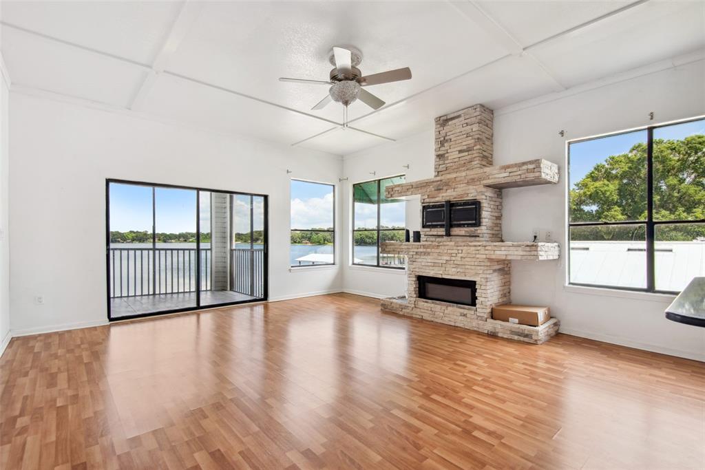 A living room with wood-look flooring, a stone fireplace, and sliding doors overlooking a lake — 3127 W SLIGH AVENUE UNIT 204B, TAMPA, FL