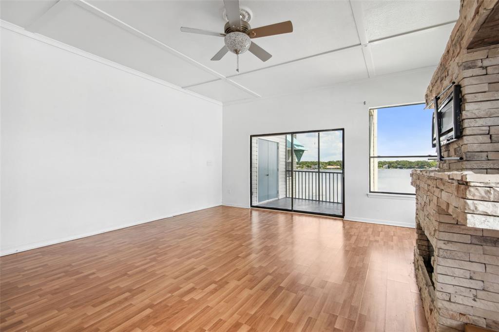 An empty living room features wood-look flooring, a stone fireplace, and a sliding glass door — 3127 W SLIGH AVENUE UNIT 204B, TAMPA, FL