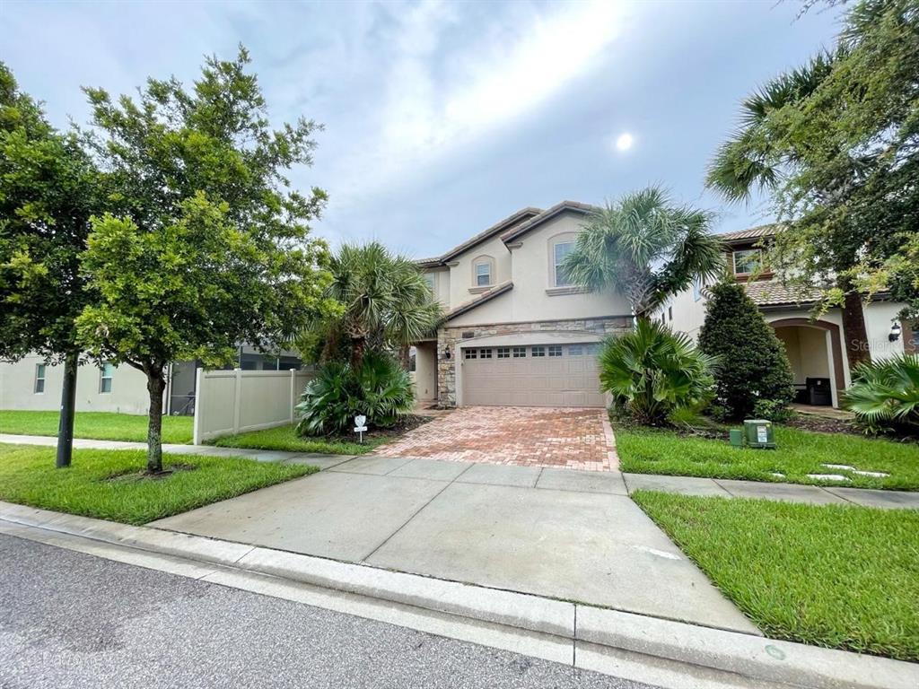 A two-story suburban house with a brick driveway, stone facade, and attached two-car garage — 2100 ROME DRIVE, KISSIMMEE, FL