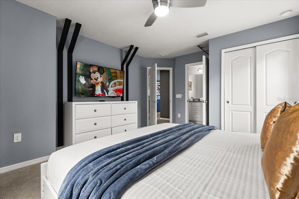 A bedroom features a white dresser, a wall-mounted television, and a bed with blue bedding — 2100 ROME DRIVE, KISSIMMEE, FL