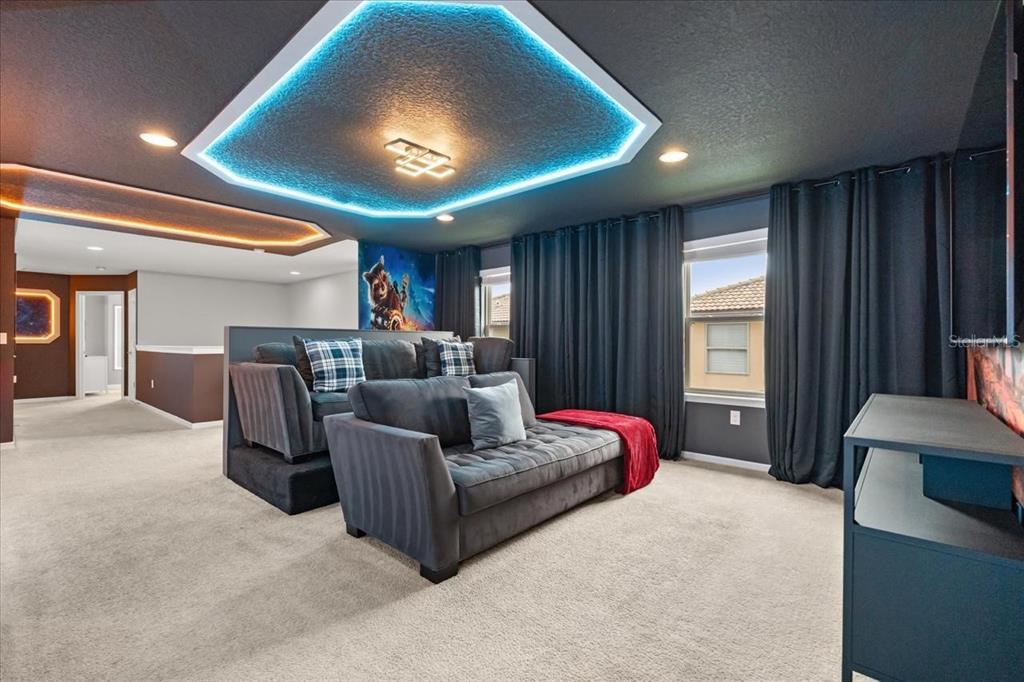 A media room features tiered gray sofas, a blue LED-lit ceiling tray, and dark curtains — 2100 ROME DRIVE, KISSIMMEE, FL
