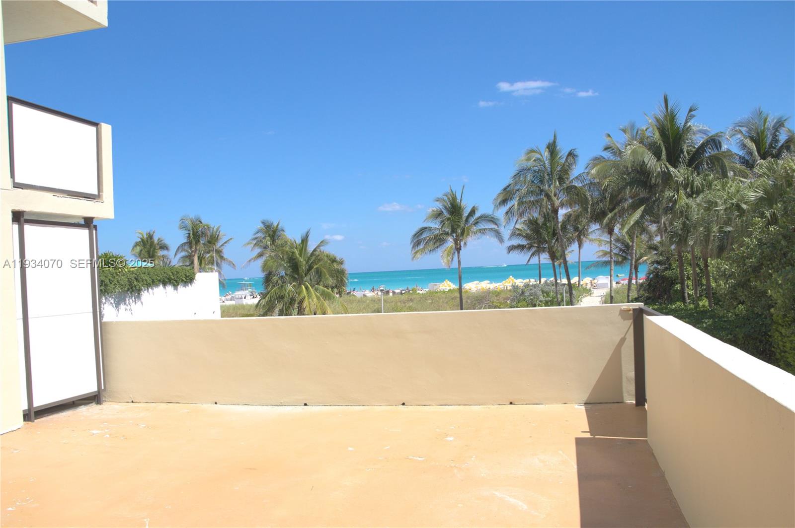 An outdoor balcony overlooks a beach with palm trees and the ocean — 1623 Collins Ave # 218, Miami Beach FL 33139, MIAMI BEACH, FL
