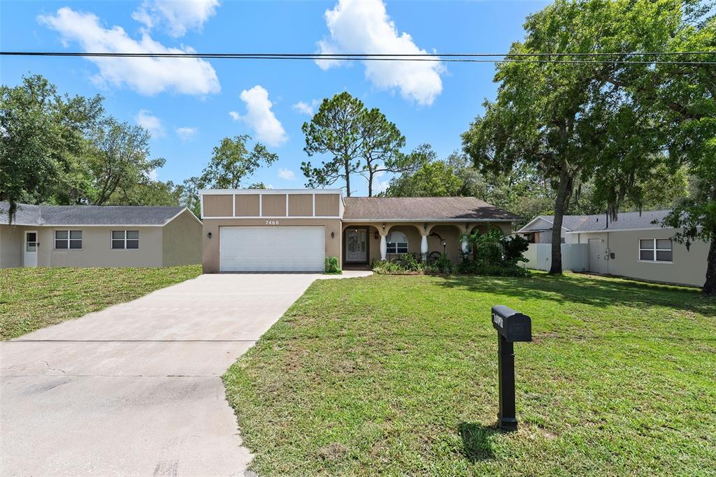 A single-story house with a two-car garage, a covered porch, and a concrete driveway — 7466 APACHE TRAIL, SPRING HILL, FL