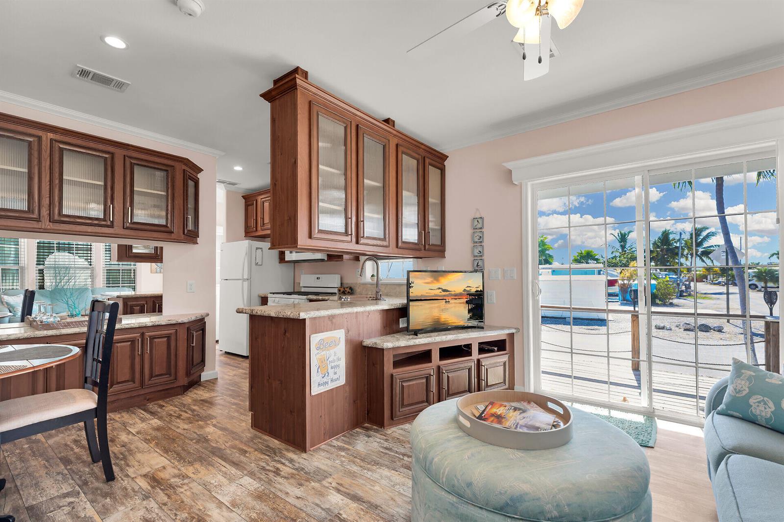 A kitchen with wood cabinets and a breakfast bar opens to a living area — 1361 Overseas Highway, Marathon FL 33050, MARATHON, FL