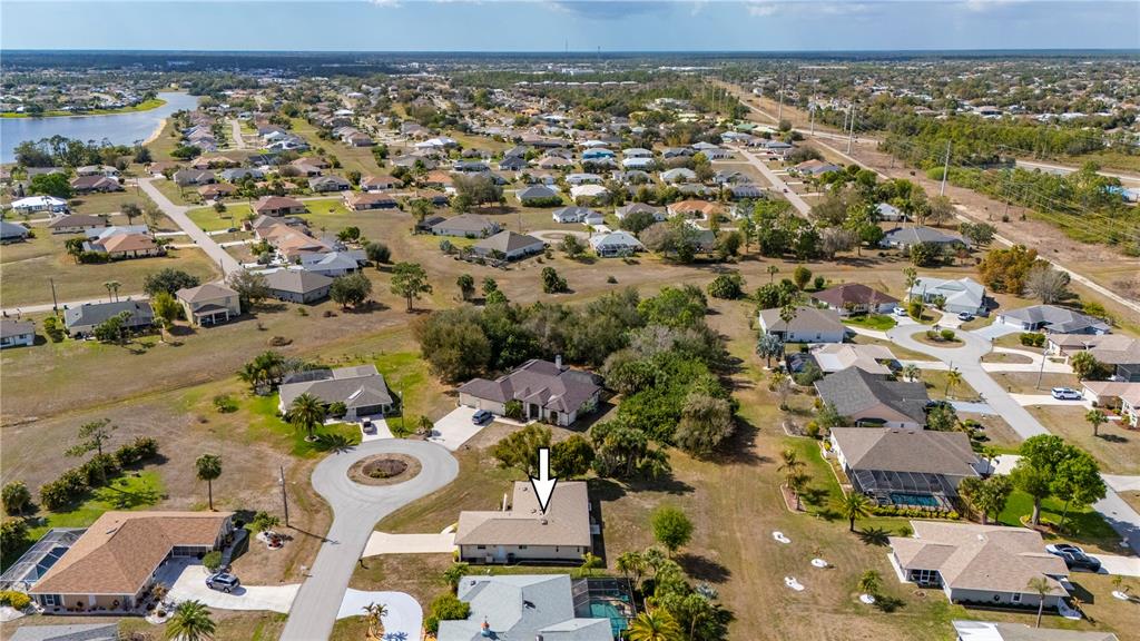 An aerial view shows a suburban neighborhood with a single-family home marked by an arrow — 26028 NORTHERN CROSS ROAD, PUNTA GORDA, FL