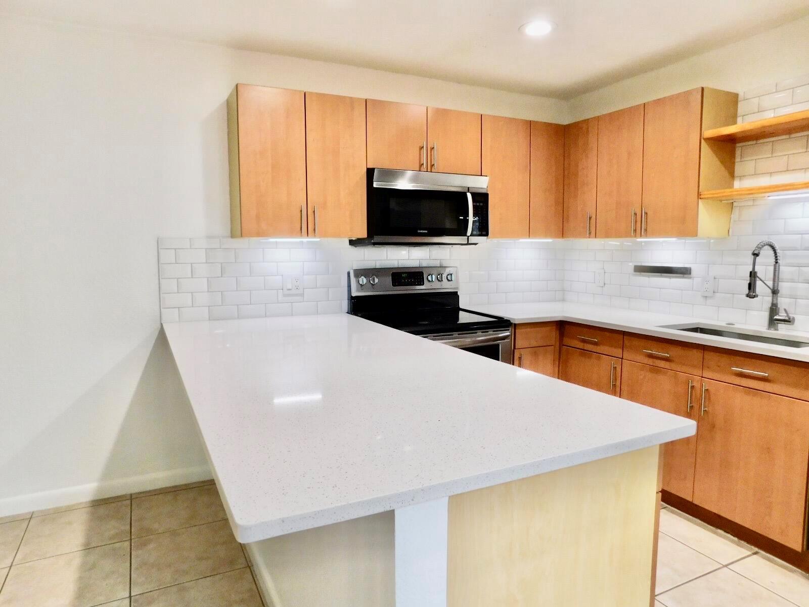 A kitchen features light wood cabinets, white quartz countertops, a subway tile backsplash, and appliances — 4155 Turnberry Circle # 29, Lake Worth FL 33467, LAKE WORTH, FL