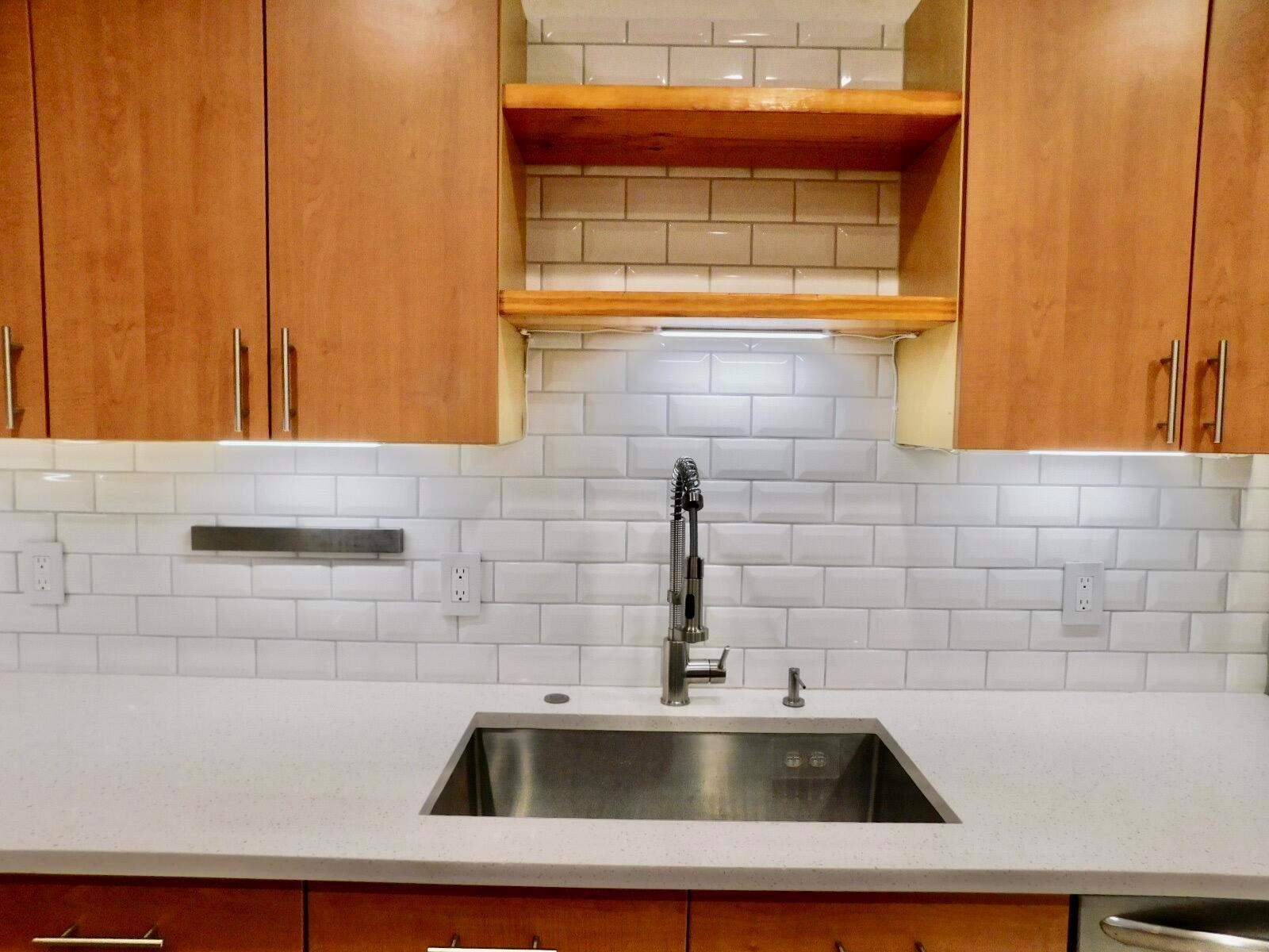 A kitchen sink area features white subway tile, wood shelving, and light wood cabinets — 4155 Turnberry Circle # 29, Lake Worth FL 33467, LAKE WORTH, FL