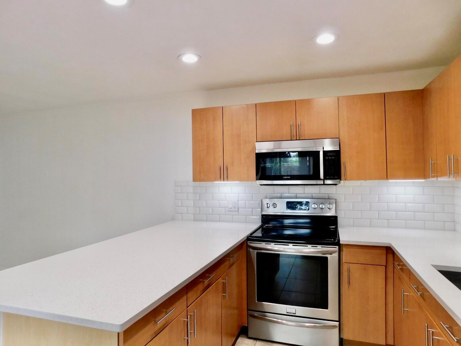 A kitchen features light wood cabinets, white quartz countertops, a subway tile backsplash, and stainless appliances — 4155 Turnberry Circle # 29, Lake Worth FL 33467, LAKE WORTH, FL