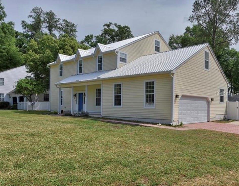 A two-story yellow house with a white metal roof and an attached garage — 525 SE 61ST COURT, OCALA, FL
