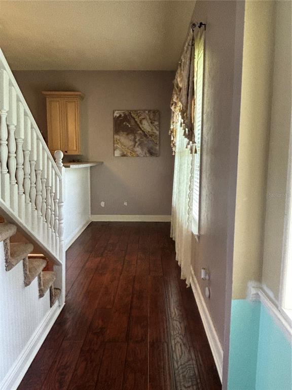 A hallway with dark wood flooring, a white staircase, and a wall-mounted cabinet — 525 SE 61ST COURT, OCALA, FL