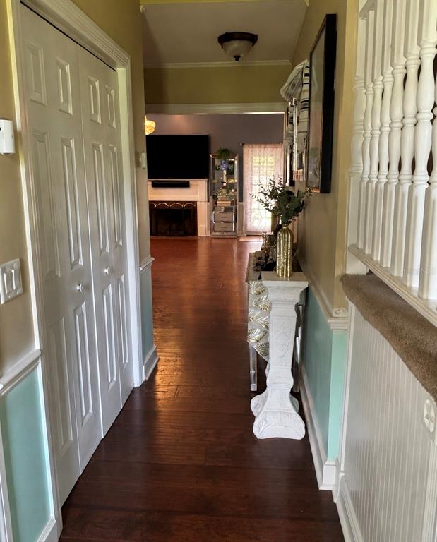 A hallway with hardwood floors leads to a living room featuring a fireplace and television — 525 SE 61ST COURT, OCALA, FL