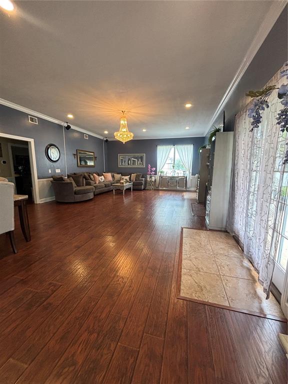 A spacious living room features dark hardwood floors, blue walls, and a large crystal chandelier — 525 SE 61ST COURT, OCALA, FL