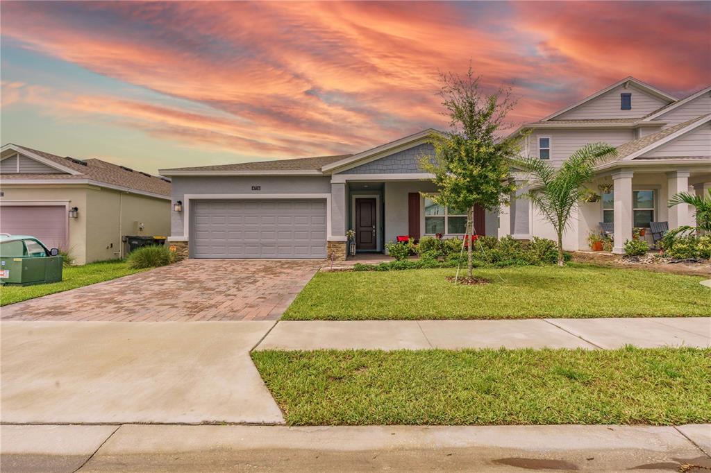 A single-story suburban house with a gray garage, brick driveway, and a small front lawn — 4716 WALTHAM FOREST DRIVE, DAVENPORT, FL