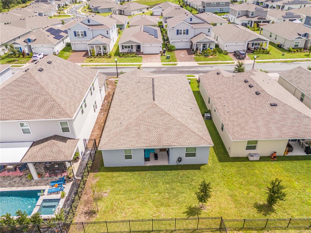 An aerial view shows the back of a suburban house with a fenced backyard — 4716 WALTHAM FOREST DRIVE, DAVENPORT, FL