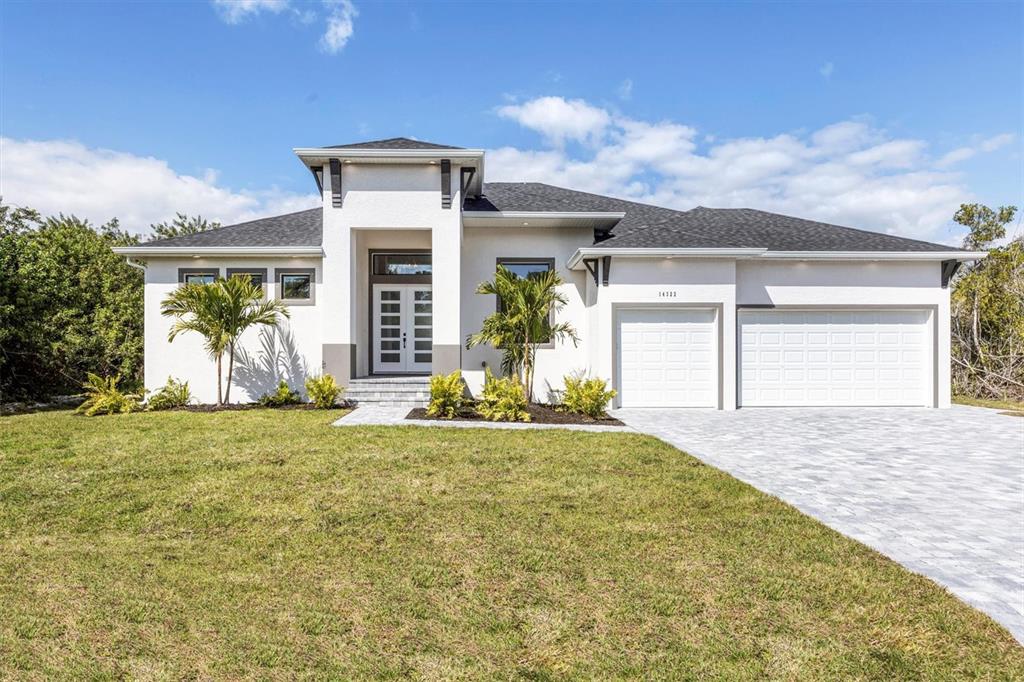 A modern single-story house with a white stucco facade, gray roof, and three-car garage — 10209 COCOA BEACH STREET, PORT CHARLOTTE, FL
