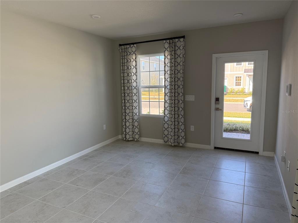 A room with light gray walls, tile flooring, a window with patterned curtains, and a door — 1200 PORT BLUE WAY, LADY LAKE, FL