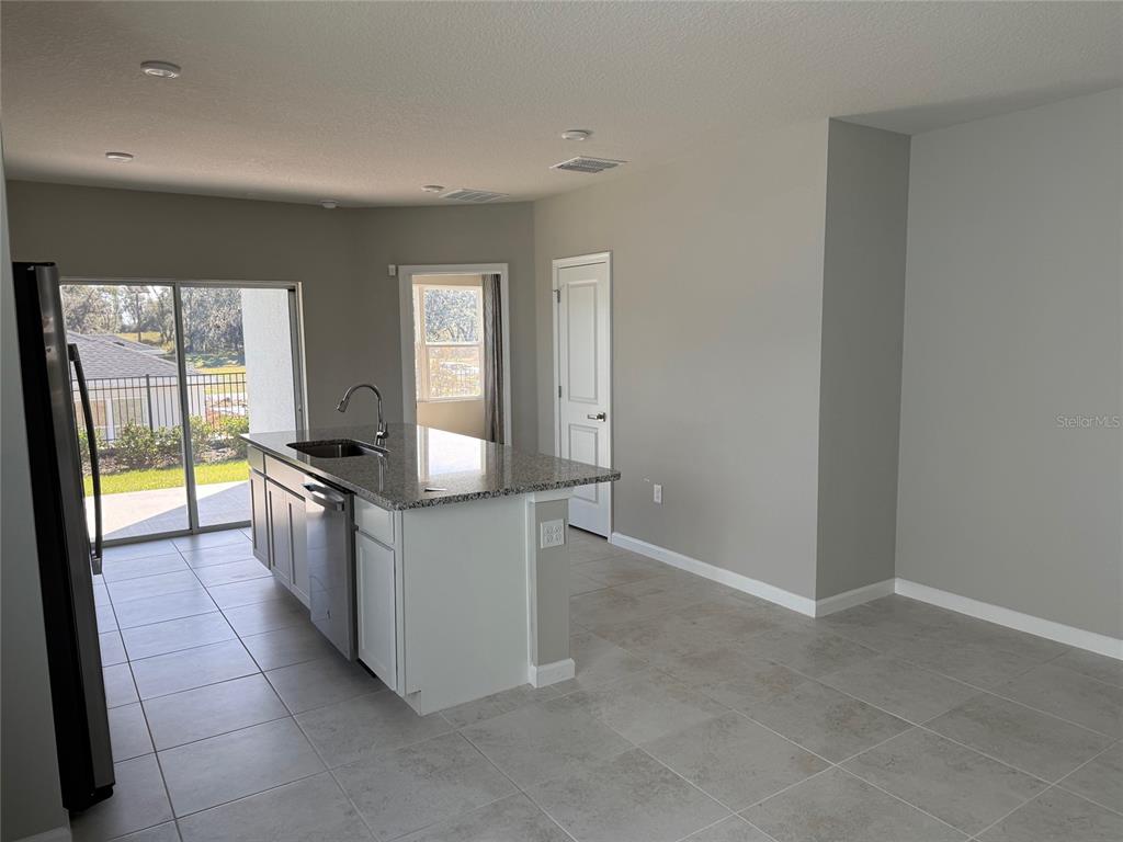A kitchen island with a granite countertop and stainless steel dishwasher sits on tile flooring — 1200 PORT BLUE WAY, LADY LAKE, FL