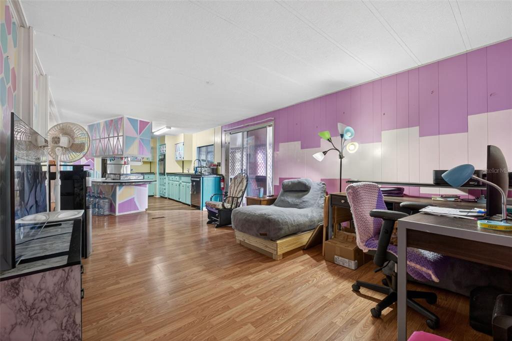 A living room with wood-look flooring, a purple paneled wall, and an open-concept kitchen — 2129 LOIS BOULEVARD, LAKE ALFRED, FL
