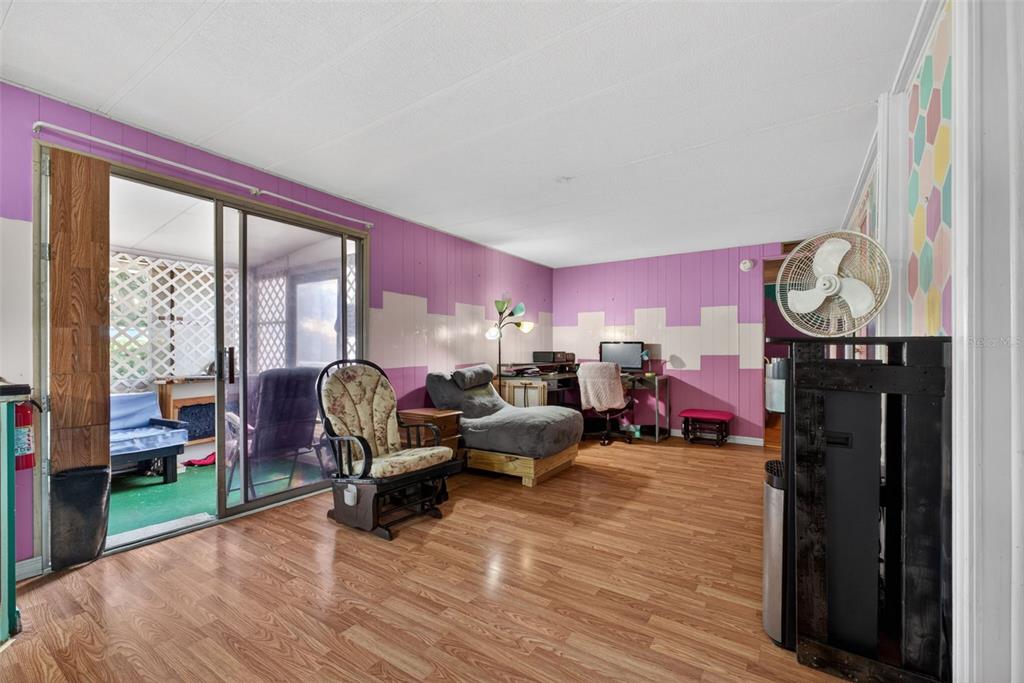 A living room features purple paneled walls, wood-look flooring, and a sliding glass door — 2129 LOIS BOULEVARD, LAKE ALFRED, FL