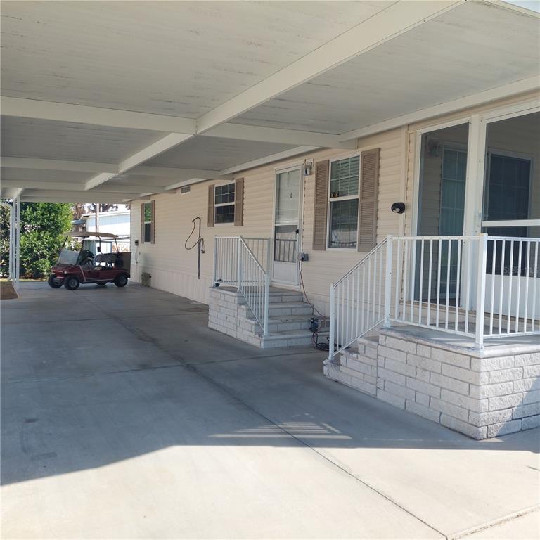 A mobile home exterior features a large concrete carport, two sets of stairs, and a golf cart — 1760 DOROTHY BOULEVARD, LUTZ, FL