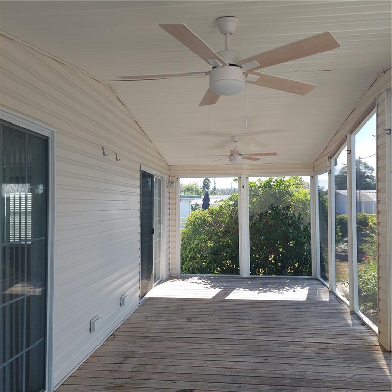 A screened-in porch with wood decking, white siding, and two ceiling fans — 1760 DOROTHY BOULEVARD, LUTZ, FL