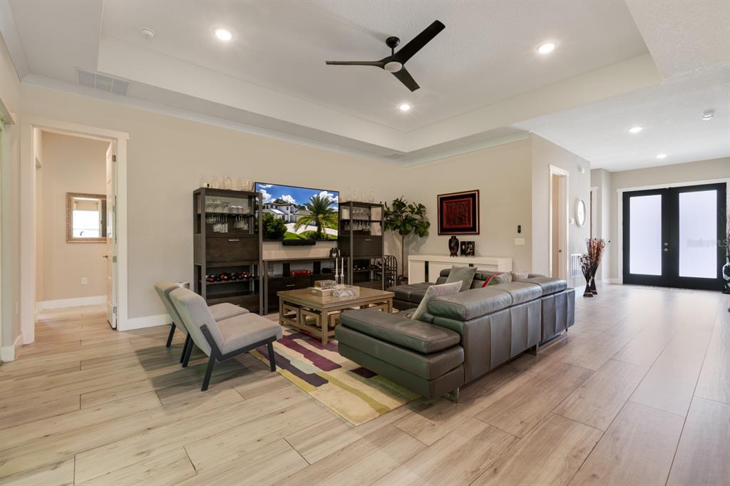 A living room features light wood-look tile flooring, a tray ceiling, and a leather sectional — 25962 HIGH HAMPTON CIRCLE, SORRENTO, FL