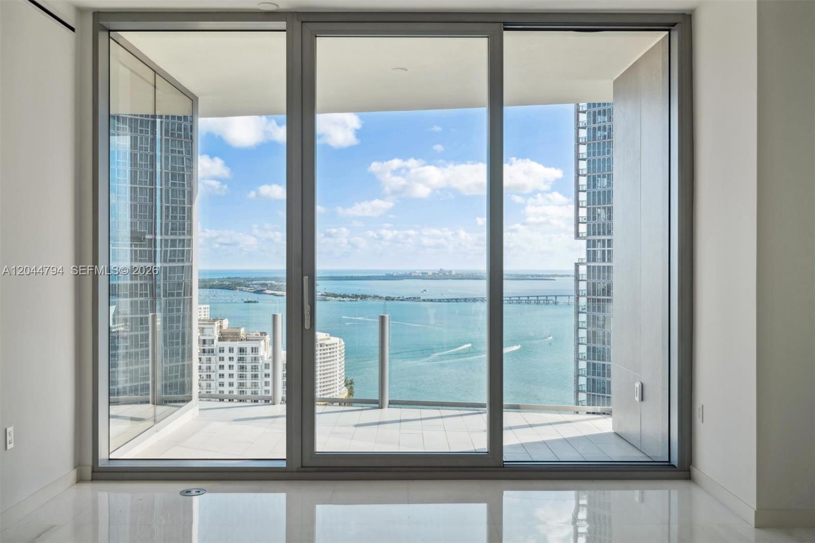 A room with white tile floors features large sliding glass doors opening to a balcony — 300 Biscayne Blvd Way # 3805W, Miami FL 33131, MIAMI, FL