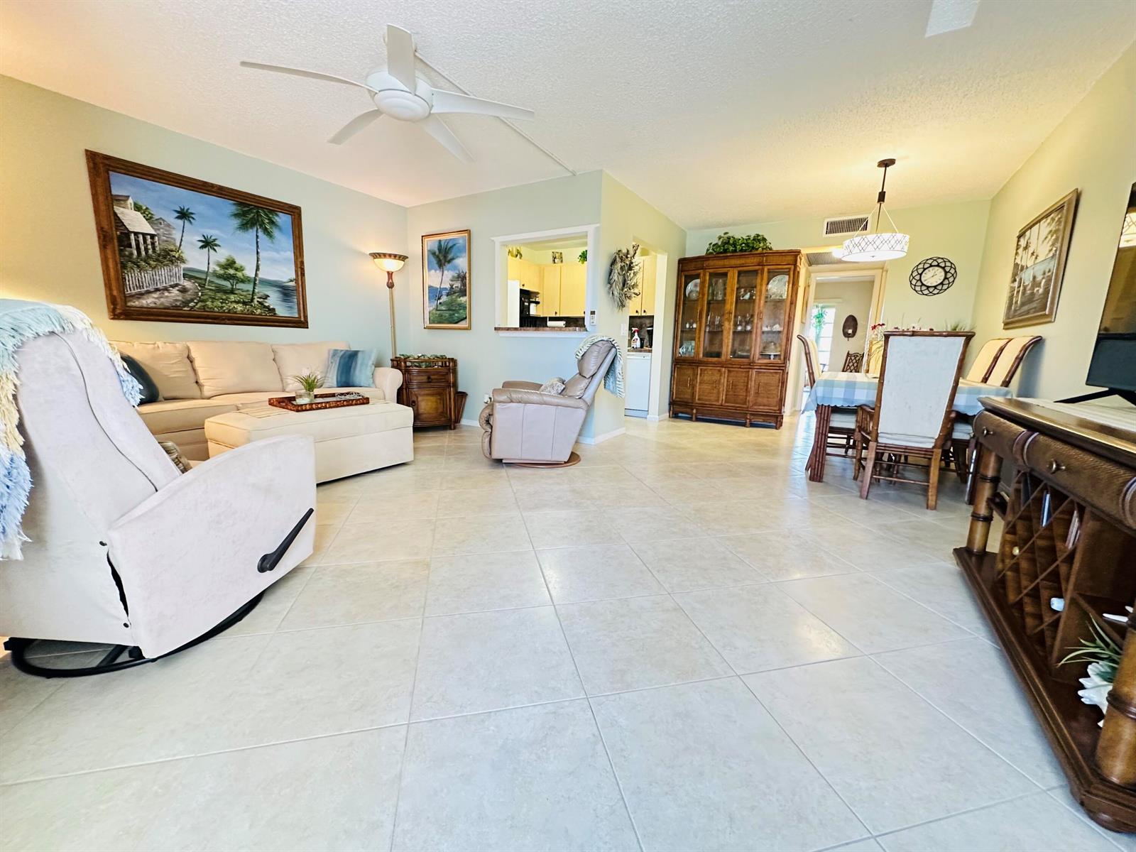 An open-concept living and dining area features light tile flooring, neutral walls, and wooden furniture — 2132 Cambridge F # 2132, Deerfield Beach FL 33442, DEERFIELD BEACH, FL