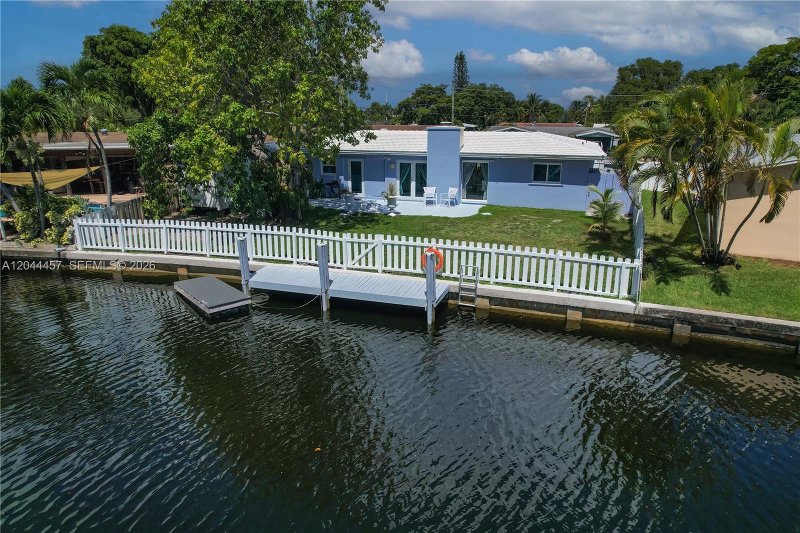 A light blue house with a white roof sits along a canal with a dock — OAKLAND PARK, FL