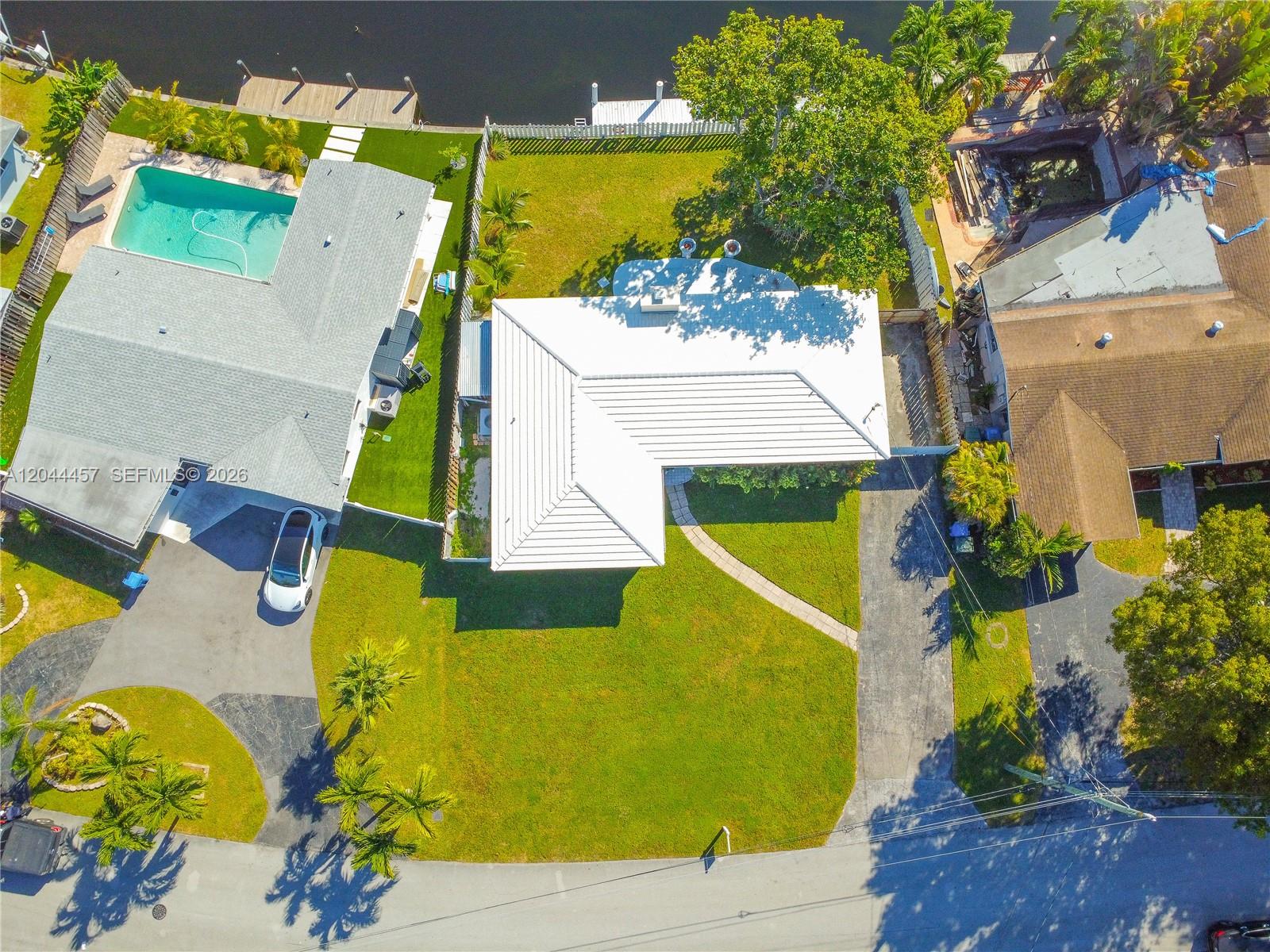 An aerial view shows a house with a white roof, a pool, and a backyard — OAKLAND PARK, FL