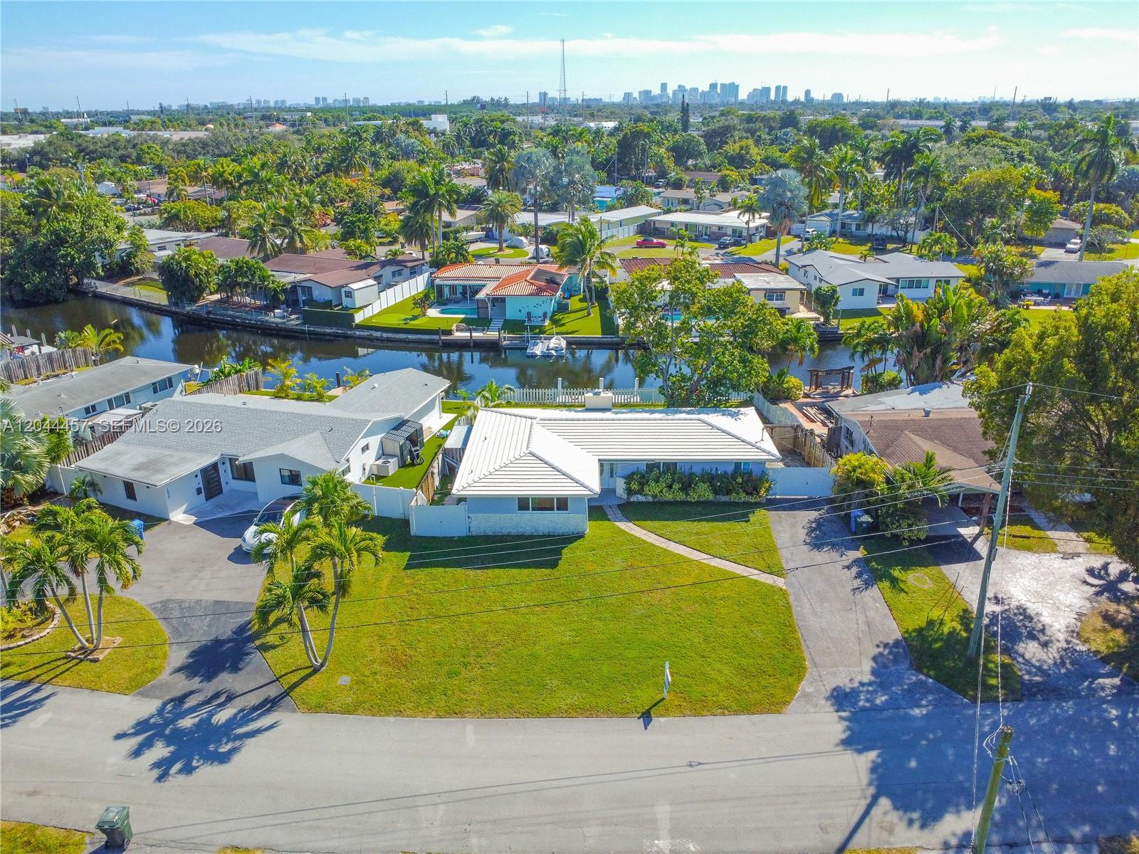 An aerial view shows two single-story houses with white roofs situated along a canal — OAKLAND PARK, FL